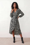 Woman wearing the Rosa Animal Print Wrap Front Midi Dress in a flowing leopard print fabric, featuring a wrap-front V-neckline, adjustable self-tie waist, long sleeves with gathered elasticated cuffs, a high-low midi hem, and a front slit, styled for weddings, cocktail parties, and elegant occasions.