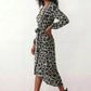 Woman wearing the Rosa Animal Print Wrap Front Midi Dress in a flowing leopard print fabric, featuring a wrap-front V-neckline, adjustable self-tie waist, long sleeves with gathered elasticated cuffs, a high-low midi hem, and a front slit, styled for weddings, cocktail parties, and elegant occasions.