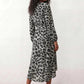 Woman wearing the Rosa Animal Print Wrap Front Midi Dress in a flowing leopard print fabric, featuring a wrap-front V-neckline, adjustable self-tie waist, long sleeves with gathered elasticated cuffs, a high-low midi hem, and a front slit, styled for weddings, cocktail parties, and elegant occasions.