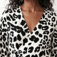 Woman wearing the Rosa Animal Print Wrap Front Midi Dress in a flowing leopard print fabric, featuring a wrap-front V-neckline, adjustable self-tie waist, long sleeves with gathered elasticated cuffs, a high-low midi hem, and a front slit, styled for weddings, cocktail parties, and elegant occasions.