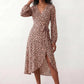 Woman wearing the Rosa Animal Print Wrap Front Midi Dress in a flowing leopard print fabric, featuring a wrap-front V-neckline, adjustable self-tie waist, long sleeves with gathered elasticated cuffs, a high-low midi hem, and a front slit, styled for weddings, cocktail parties, and elegant occasions.