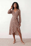 Woman wearing the Rosa Animal Print Wrap Front Midi Dress in a flowing leopard print fabric, featuring a wrap-front V-neckline, adjustable self-tie waist, long sleeves with gathered elasticated cuffs, a high-low midi hem, and a front slit, styled for weddings, cocktail parties, and elegant occasions.
