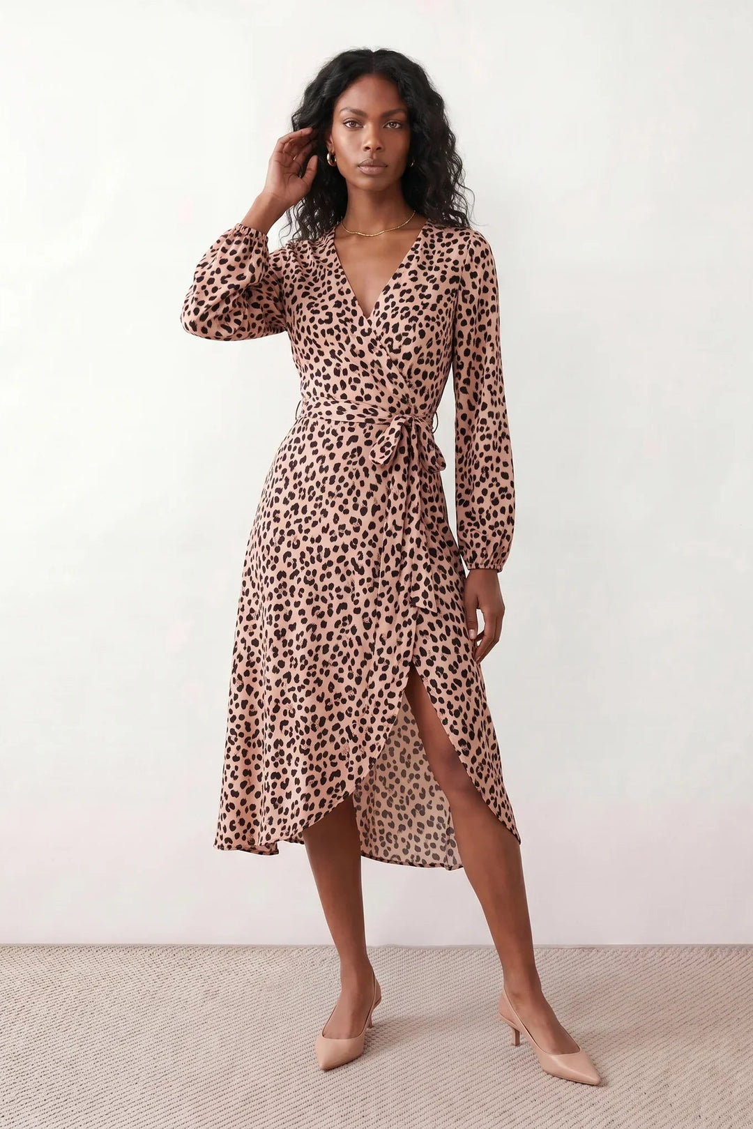 Woman wearing the Rosa Animal Print Wrap Front Midi Dress in a flowing leopard print fabric, featuring a wrap-front V-neckline, adjustable self-tie waist, long sleeves with gathered elasticated cuffs, a high-low midi hem, and a front slit, styled for weddings, cocktail parties, and elegant occasions.