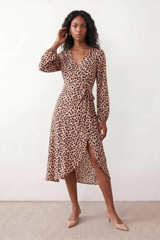 Woman wearing the Rosa Animal Print Wrap Front Midi Dress in a flowing leopard print fabric, featuring a wrap-front V-neckline, adjustable self-tie waist, long sleeves with gathered elasticated cuffs, a high-low midi hem, and a front slit, styled for weddings, cocktail parties, and elegant occasions.
