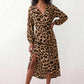 Woman wearing the Rosa Animal Print Wrap Front Midi Dress in a flowing leopard print fabric, featuring a wrap-front V-neckline, adjustable self-tie waist, long sleeves with gathered elasticated cuffs, a high-low midi hem, and a front slit, styled for weddings, cocktail parties, and elegant occasions.