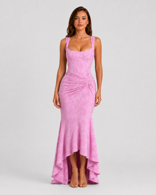 Woman wearing a textured floral corset maxi dress featuring a structured bodice, ruched waist, and dramatic high-low fishtail hem for elegant evening occasions.