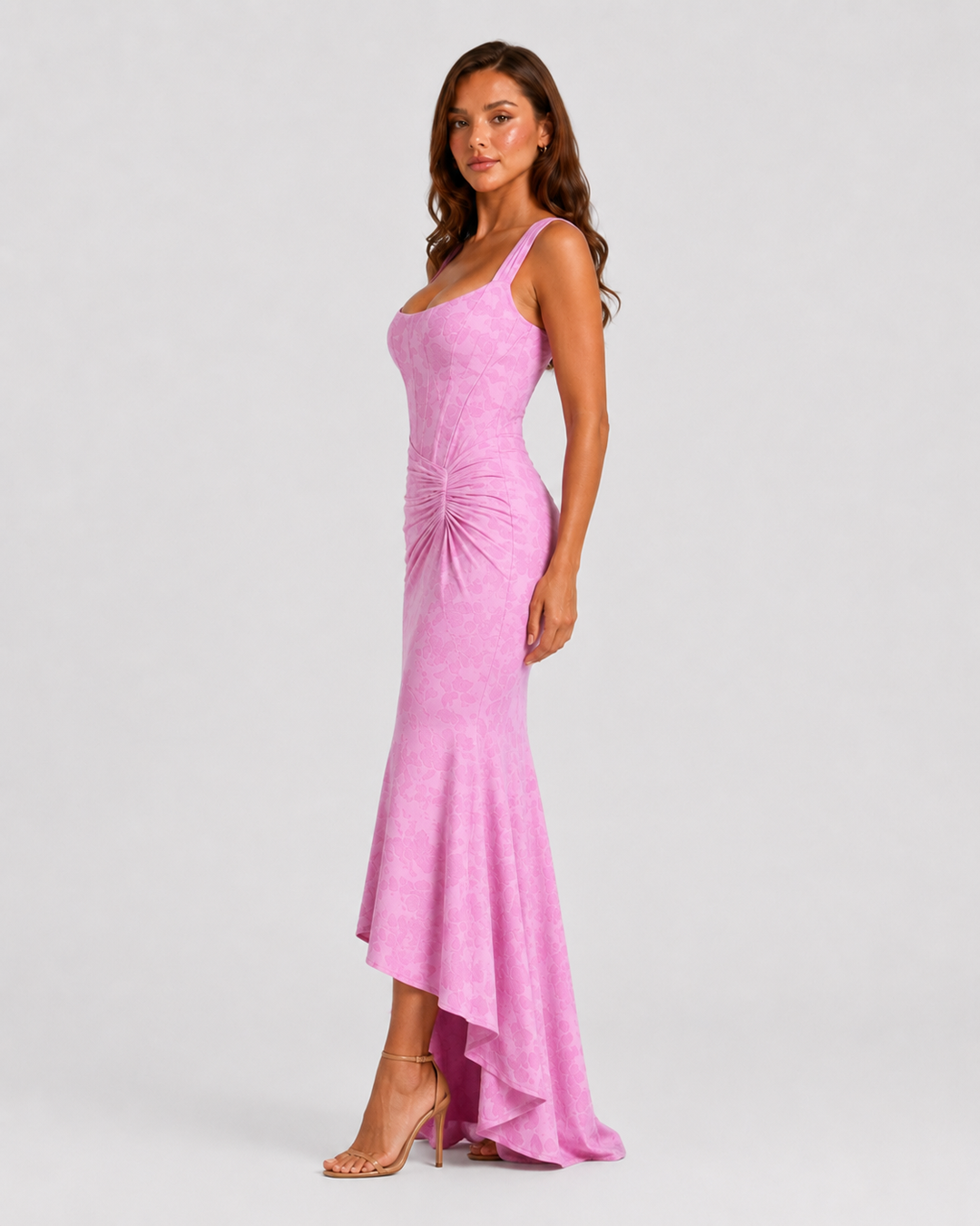 Woman wearing a textured floral corset maxi dress featuring a structured bodice, ruched waist, and dramatic high-low fishtail hem for elegant evening occasions.