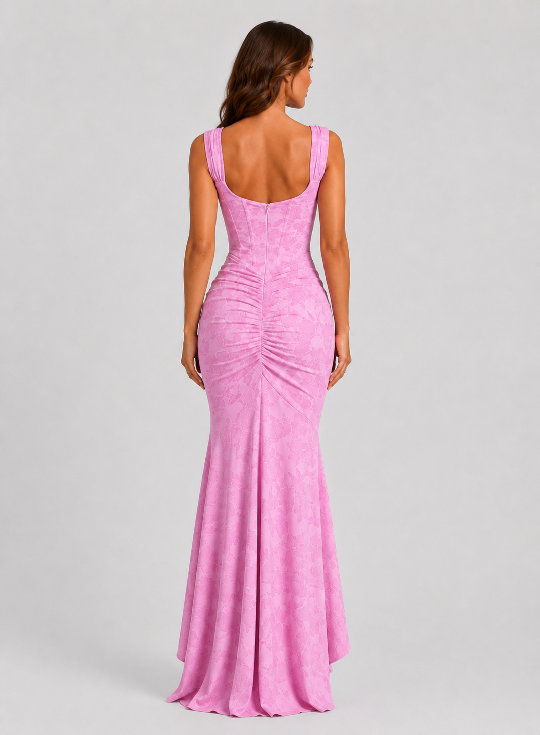 Woman wearing a textured floral corset maxi dress featuring a structured bodice, ruched waist, and dramatic high-low fishtail hem for elegant evening occasions.