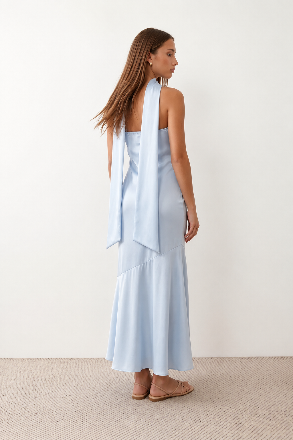 Woman wearing the Diana satin strapless maxi dress featuring a square neckline, scarf-style choker tie, open back with draped detail, and a floor-length fitted silhouette in a smooth satin finish.
