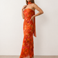 Woman wearing the Diana satin strapless maxi dress featuring a square neckline, scarf-style choker tie, open back with draped detail, and a floor-length fitted silhouette in a smooth satin finish.