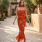 Woman wearing the Diana satin strapless maxi dress featuring a square neckline, scarf-style choker tie, open back with draped detail, and a floor-length fitted silhouette in a smooth satin finish.