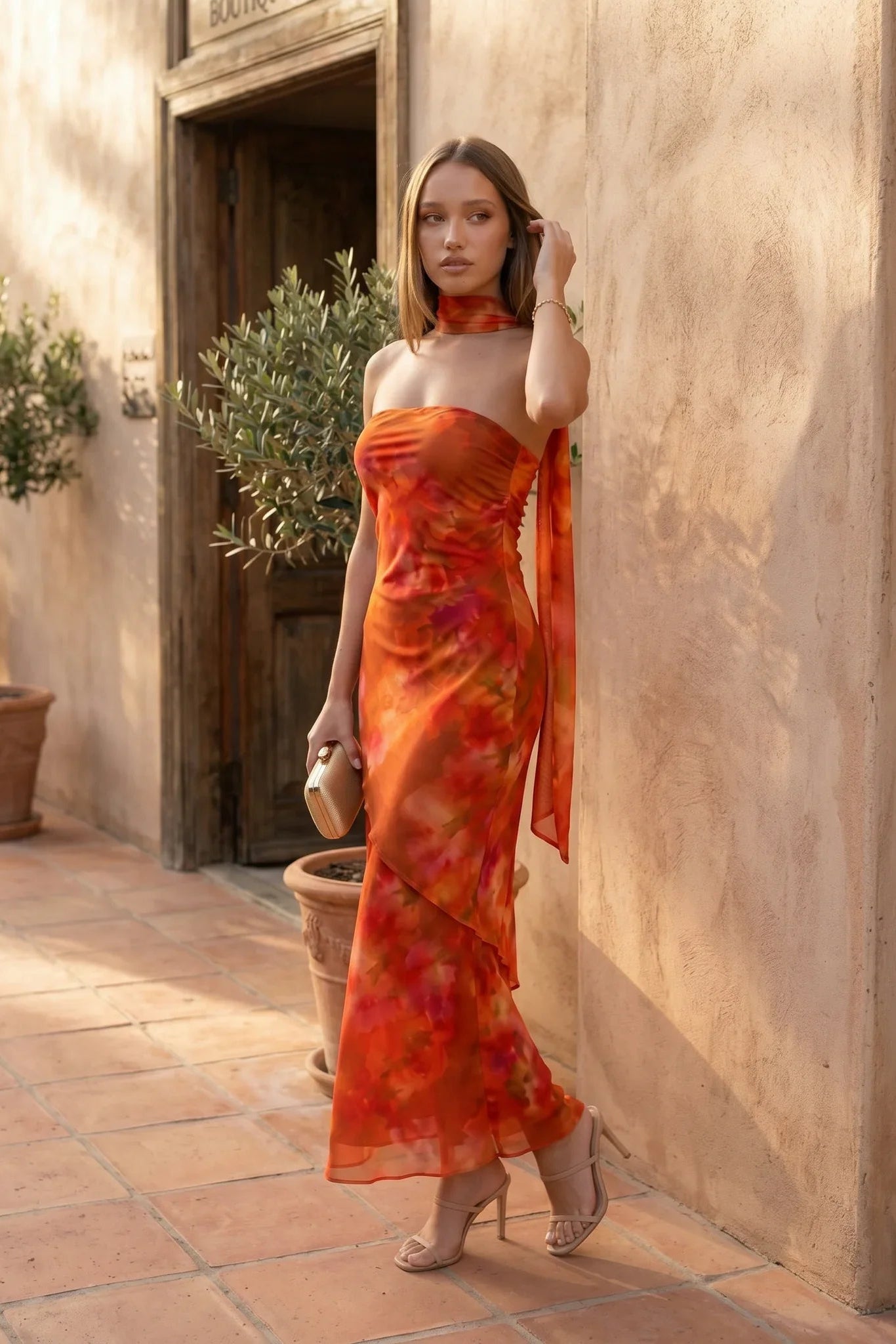 Woman wearing the Diana satin strapless maxi dress featuring a square neckline, scarf-style choker tie, open back with draped detail, and a floor-length fitted silhouette in a smooth satin finish.
