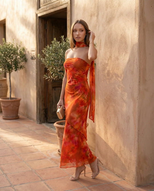Woman wearing the Diana satin strapless maxi dress featuring a square neckline, scarf-style choker tie, open back with draped detail, and a floor-length fitted silhouette in a smooth satin finish.