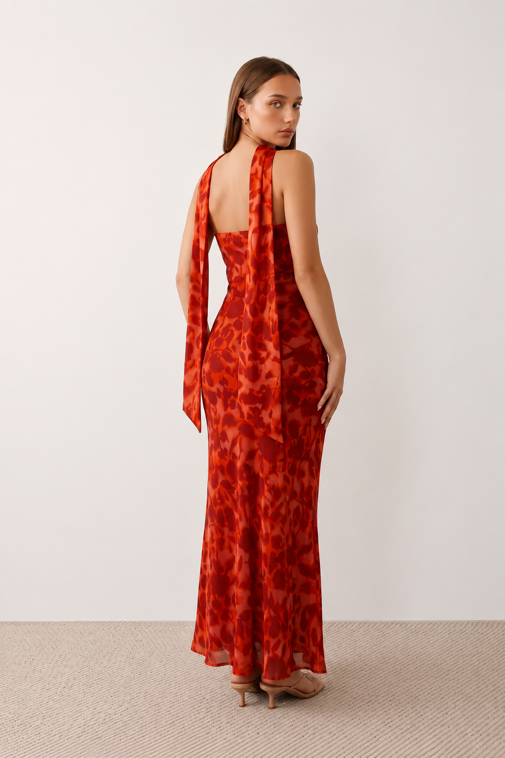 Woman wearing the Diana satin strapless maxi dress featuring a square neckline, scarf-style choker tie, open back with draped detail, and a floor-length fitted silhouette in a smooth satin finish.