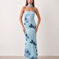 Woman wearing the Diana satin strapless maxi dress featuring a square neckline, scarf-style choker tie, open back with draped detail, and a floor-length fitted silhouette in a smooth satin finish.