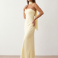 Woman wearing the Diana satin strapless maxi dress featuring a square neckline, scarf-style choker tie, open back with draped detail, and a floor-length fitted silhouette in a smooth satin finish.