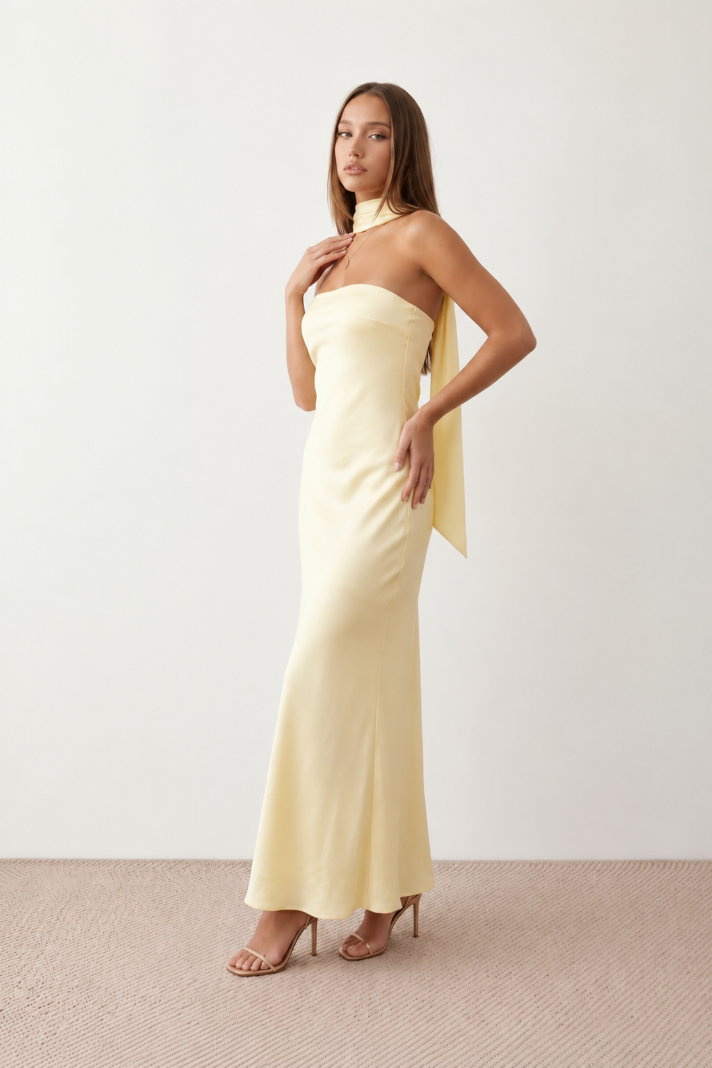 Woman wearing the Diana satin strapless maxi dress featuring a square neckline, scarf-style choker tie, open back with draped detail, and a floor-length fitted silhouette in a smooth satin finish.