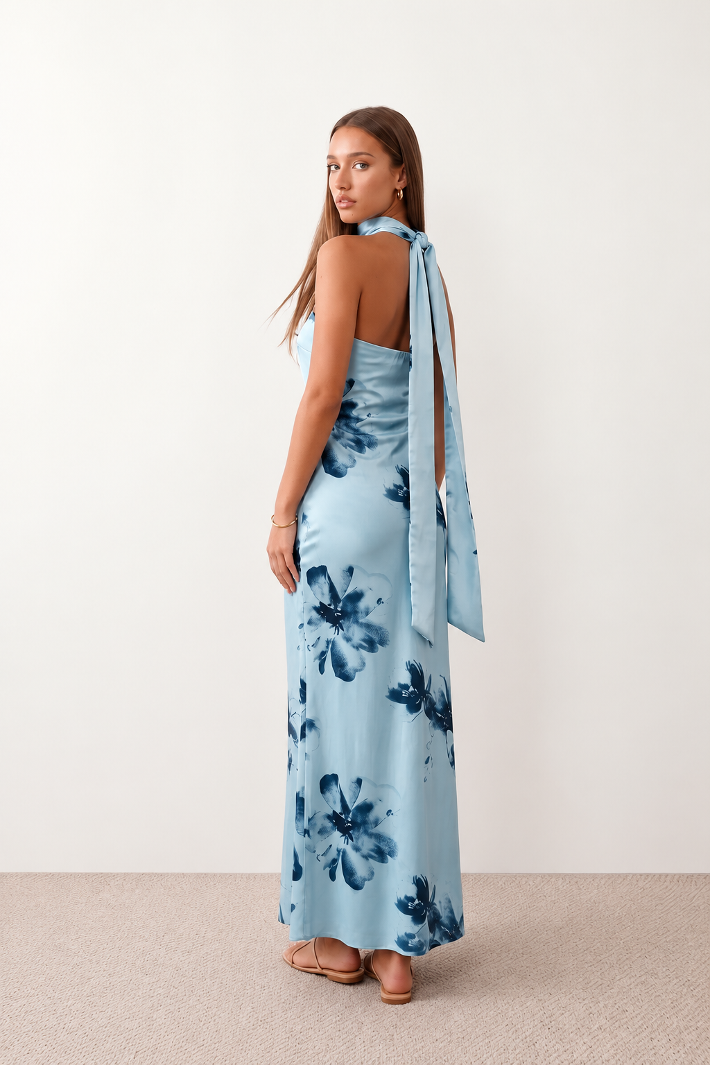 Woman wearing the Diana satin strapless maxi dress featuring a square neckline, scarf-style choker tie, open back with draped detail, and a floor-length fitted silhouette in a smooth satin finish.