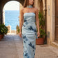 Woman wearing the Diana satin strapless maxi dress featuring a square neckline, scarf-style choker tie, open back with draped detail, and a floor-length fitted silhouette in a smooth satin finish.