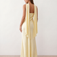 Woman wearing the Diana satin strapless maxi dress featuring a square neckline, scarf-style choker tie, open back with draped detail, and a floor-length fitted silhouette in a smooth satin finish.