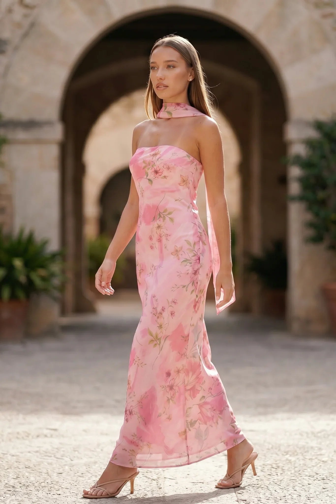 Woman wearing the Diana satin strapless maxi dress featuring a square neckline, scarf-style choker tie, open back with draped detail, and a floor-length fitted silhouette in a smooth satin finish.
