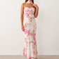 Woman wearing the Diana satin strapless maxi dress featuring a square neckline, scarf-style choker tie, open back with draped detail, and a floor-length fitted silhouette in a smooth satin finish.