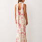 Woman wearing the Diana satin strapless maxi dress featuring a square neckline, scarf-style choker tie, open back with draped detail, and a floor-length fitted silhouette in a smooth satin finish.