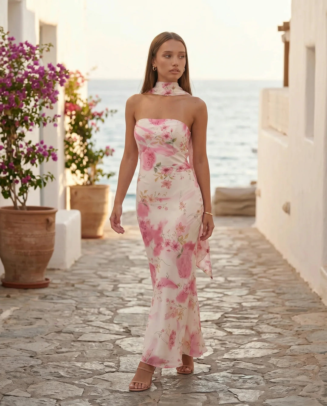 Woman wearing the Diana satin strapless maxi dress featuring a square neckline, scarf-style choker tie, open back with draped detail, and a floor-length fitted silhouette in a smooth satin finish.