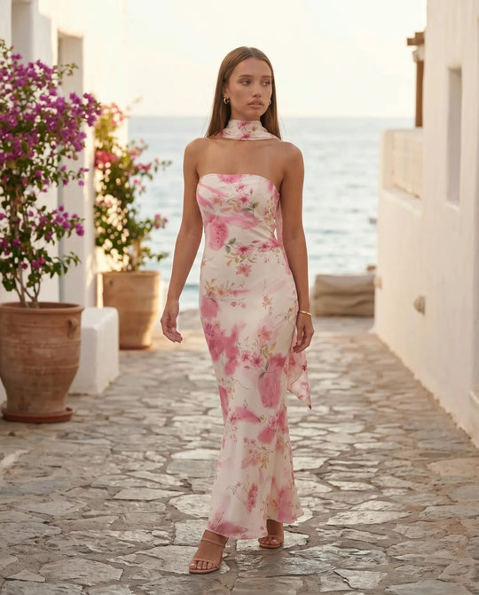 Woman wearing the Diana satin strapless maxi dress featuring a square neckline, scarf-style choker tie, open back with draped detail, and a floor-length fitted silhouette in a smooth satin finish.