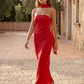 Woman wearing the Diana satin strapless maxi dress featuring a square neckline, scarf-style choker tie, open back with draped detail, and a floor-length fitted silhouette in a smooth satin finish.