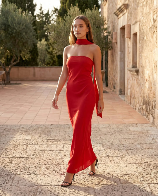 Woman wearing the Diana satin strapless maxi dress featuring a square neckline, scarf-style choker tie, open back with draped detail, and a floor-length fitted silhouette in a smooth satin finish.