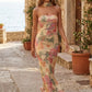 Woman wearing the Diana satin strapless maxi dress featuring a square neckline, scarf-style choker tie, open back with draped detail, and a floor-length fitted silhouette in a smooth satin finish.