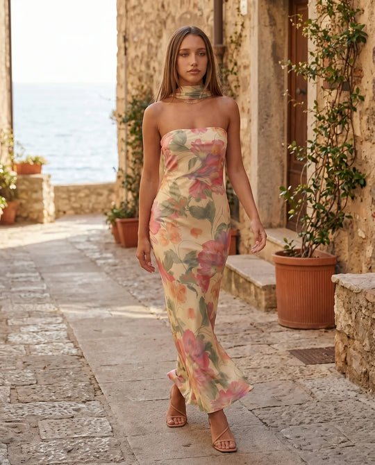 Woman wearing the Diana satin strapless maxi dress featuring a square neckline, scarf-style choker tie, open back with draped detail, and a floor-length fitted silhouette in a smooth satin finish.