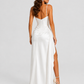 Women’s draped satin maxi dress featuring a fitted bodice, asymmetric waist draping, and a flowing split skirt for elegant evening occasions.