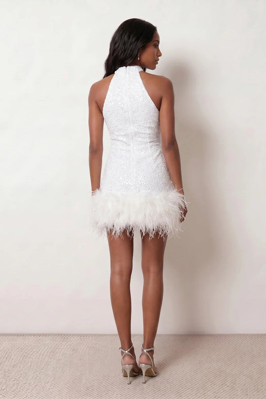 Woman wearing the Shanna Sequined Halter Mini Dress featuring all-over shimmering sequins, an elegant halter neckline, striking open back, fitted sheath silhouette, and soft feather-trimmed mini hem, perfect for parties, cocktail events and festive occasions.