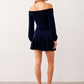 Woman wearing the Silviana Glossy Bardot Mini Dress featuring a glossy finish, off-shoulder Bardot neckline with soft shirring, centre front bow detail, long sleeves and a flattering dropped waist silhouette, styled for parties and evening occasions.