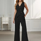Woman wearing a black sleeveless blazer and wide-leg pants in a neutral setting