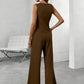 Woman wearing a brown jumpsuit in a minimalistic room.