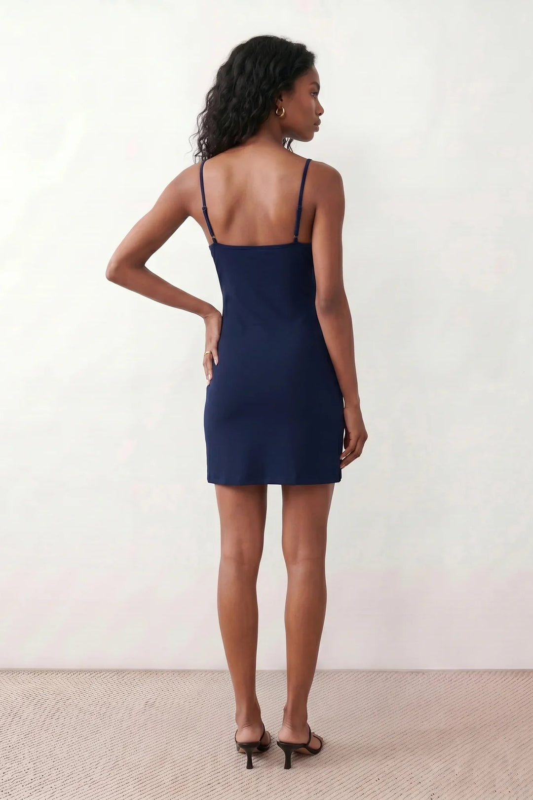 Woman wearing the spaghetti strap low back fitted mini dress featuring adjustable straps, a figure-hugging sheath silhouette, elegant low open back, side slit, and mini-length hem, perfect for parties, weddings, and evening occasions.