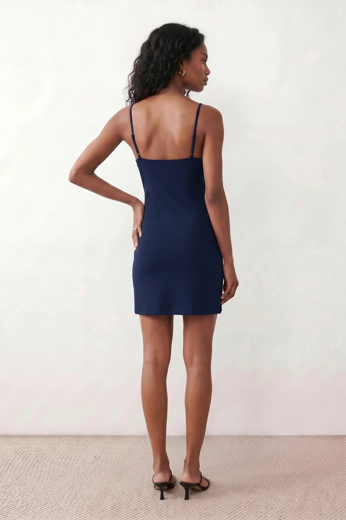 Woman wearing the spaghetti strap low back fitted mini dress featuring adjustable straps, a figure-hugging sheath silhouette, elegant low open back, side slit, and mini-length hem, perfect for parties, weddings, and evening occasions.