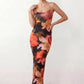 Women's spaghetti strap floral maxi dress with a fitted sheath silhouette, round neckline, adjustable straps, and elegant low open back in a red and black floral print, perfect for weddings and special occasions.