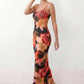 Women's spaghetti strap floral maxi dress with a fitted sheath silhouette, round neckline, adjustable straps, and elegant low open back in a red and black floral print, perfect for weddings and special occasions.