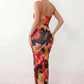 Women's spaghetti strap floral maxi dress with a fitted sheath silhouette, round neckline, adjustable straps, and elegant low open back in a red and black floral print, perfect for weddings and special occasions.