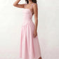 Woman wearing a spaghetti strap low back midi dress with a square neckline, ruched ruffle bodice, adjustable tie shoulder straps, elasticated smocked back, and flowing A-line skirt, styled as an elegant wedding guest and summer occasion dress.