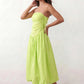 Woman wearing a spaghetti strap low back midi dress with a square neckline, ruched ruffle bodice, adjustable tie shoulder straps, elasticated smocked back, and flowing A-line skirt, styled as an elegant wedding guest and summer occasion dress.