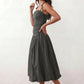 Woman wearing a spaghetti strap low back midi dress with a square neckline, ruched ruffle bodice, adjustable tie shoulder straps, elasticated smocked back, and flowing A-line skirt, styled as an elegant wedding guest and summer occasion dress.