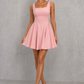 Women’s square neck pleated mini dress featuring delicate shoulder straps, a fitted bodice, and a flowing A-line skirt in soft pale pink for parties and special occasions.