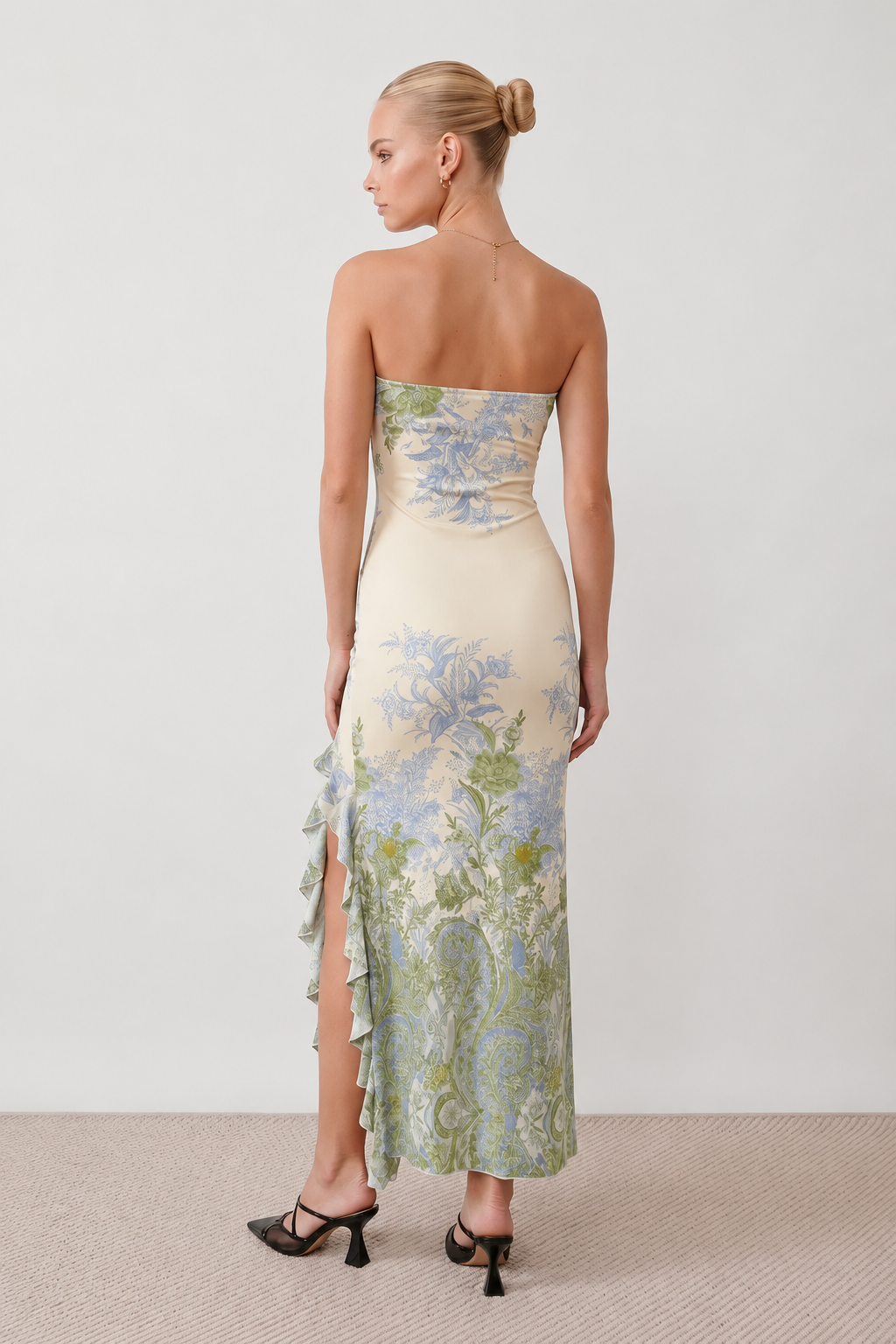 Woman wearing the Madelyn Strapless Floral Maxi Dress featuring a strapless square neckline, fitted bodice, botanical floral print, cascading layered ruffle front split, and flowing maxi-length skirt, ideal for weddings, race days, garden parties, and formal occasions.