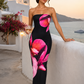 Woman wearing a strapless floral print midi dress with a fitted bodice and fit-and-flare silhouette in soft jersey fabric, ideal for wedding guests, garden parties, and special occasions.