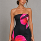 Woman wearing a strapless floral print midi dress with a fitted bodice and fit-and-flare silhouette in soft jersey fabric, ideal for wedding guests, garden parties, and special occasions.
